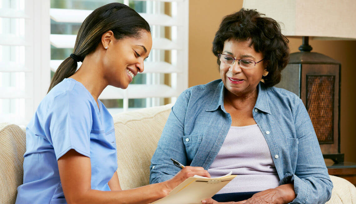 Health care service provider attending to a black American senior at home.